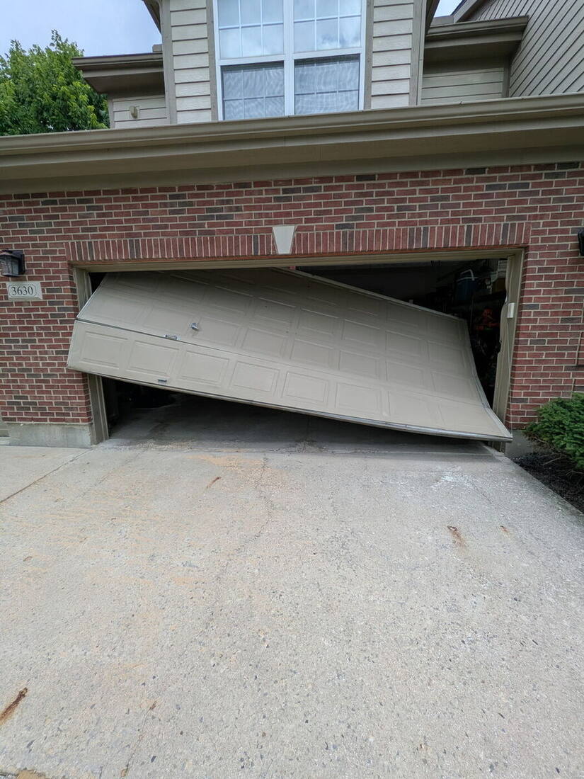 Residential garage door hanging off its tracks after coming off the rollers in Dayton, Ohio